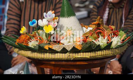 Nasi Tumpeng (Konusreis) serviert mit Urap-Uap (indonesischer Salat), gebratenem Hähnchen und Nudeln. Nasi-Tumpeng wird normalerweise auf Geburtstagspartys serviert Stockfoto