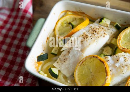 Gebackener Kabeljau mit Gemüse, Zitrone und Zucchini. Stockfoto