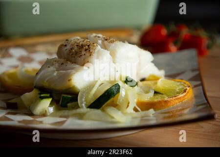 Gebackener Kabeljau mit Gemüse, Zitrone und Zucchini. Stockfoto