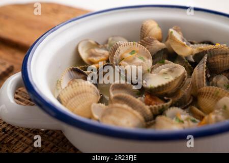 Cockles mit grünem Knoblauch und Petersiliensoße. Traditionelle spanische Fischtapa. Stockfoto