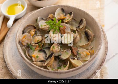 Cockles mit grünem Knoblauch und Petersiliensoße. Traditionelle spanische Fischtapa. Stockfoto