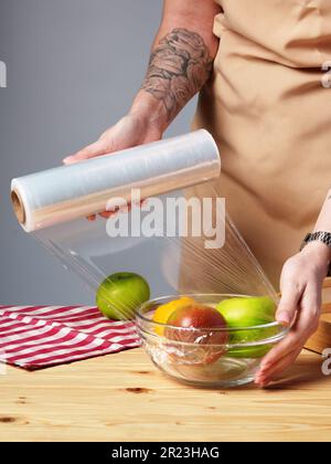 Eine Frau, die eine Schüssel frisches Obst auf einen Holztisch stellt Stockfoto