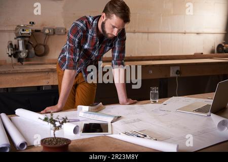 Es ist alles für ihn geplant. Ein gutaussehender junger Mann in seiner Werkstatt. Stockfoto