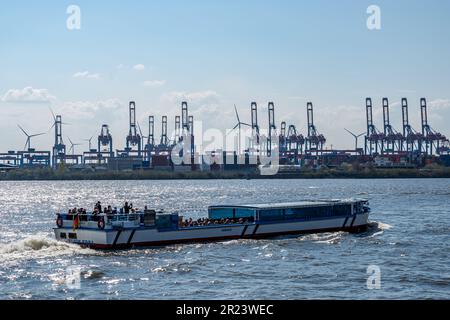 Hamburg, Deutschland - 04 17 2023: Touristen machen eine Kutschfahrt im hamburger Hafen gegen Licht und in den Containerkränen im Hintergrund. Stockfoto