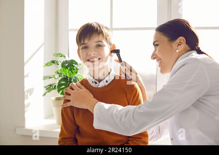 Eine Otoskop-Oto-Laryngologin untersucht einen glücklichen Jungen Stockfoto