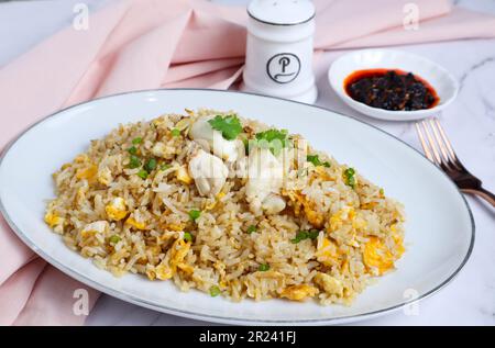 Crab Fried Rice: Asiatische Gerichte werden an einem weißen Marmortisch serviert, von dem aus man aus die Umgebung sehen kann Stockfoto