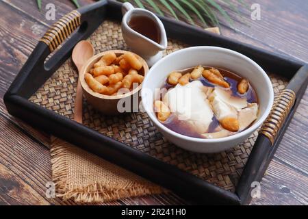 Douhua - weicher Tofu-Pudding (Sojabohnenquetsch), asiatisches berühmtes gesundes Dessert, serviert in Bambus-Tablett aus Holz bei Nahaufnahme Stockfoto