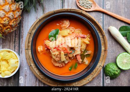Rote Curry mit Ananas und Garnelen – authentische thailändische Gerichte namens Kang Kua Supparos von oben auf einem Holztisch Stockfoto