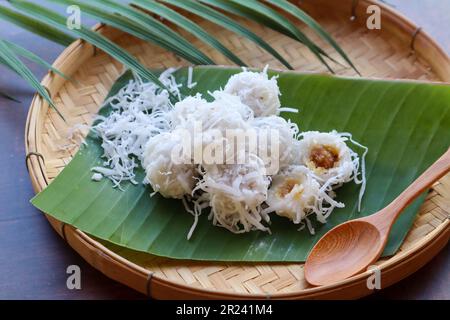 Kanom Tom: Thailändisches Dessert aus gekochtem Reismehl, mit Kokosnuss überzogen und von oben mit Palmzucker geschmolzener Kokosnuss gefüllt Stockfoto