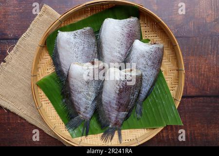 Sonnengetrockneter, ungekochter Gourami-Fisch - auf Thailändisch mit dem Namen Pla Salit auf einem Bambuskorb von oben Stockfoto