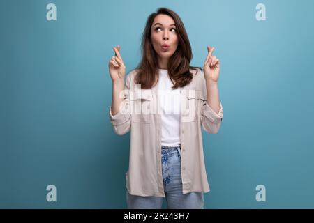 Eine hübsche 25-jährige Frau in einem lässigen Look zeigt mit ihren Zeigefingern an die Wand Stockfoto