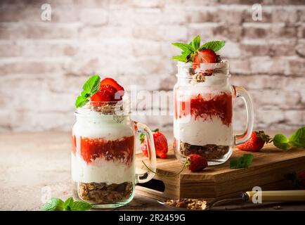 Gesundes Frühstück in einem Mason-Glas mit Joghurt, Erdbeerpüree und Müsli Stockfoto