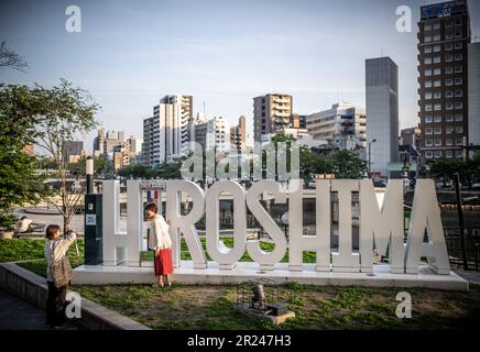 Hiroshima, Japan. 17. Mai 2023. Zwei Passanten stehen vor einem Hiroshima-Schild auf der Skyline der Stadt, wo die erste Atombombe in Südjapan abgelegt wurde. Ab 19,5. Auf 21,05 treffen sich die Regierungschefs der G7 Länder zu einem Gipfeltreffen. Kredit: Michael Kappeler/dpa/Alamy Live News Stockfoto