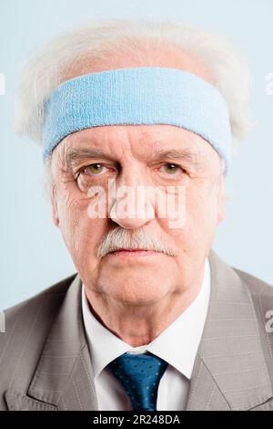 Ich werde zu alt dafür. Ein älterer Mann, der allein im Studio steht und posiert, während er ein Stirnband trägt. Stockfoto