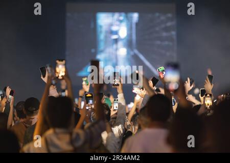 Die Leute drehen das Konzert mit ihren Handys Stockfoto