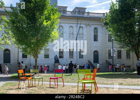 Boston, Massachusetts, USA – September 2022; Blick auf den Harvard Yard der Harvard University mit seinen farbenfrohen luxemburgischen Stühlen vor dem Gebäude und dem Universitätssaal Stockfoto