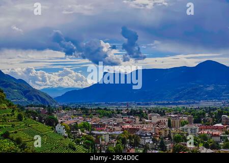 Ein Luftblick auf eine Stadt mit Blick auf ein bergiges Tal in Südtirol, Merano, Italien Stockfoto