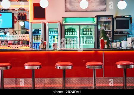 Retro, Vintage und Hocker mit Inneneinrichtung in einem Diner, Restaurant oder Cafeteria mit flippiger Einrichtung. Trendy, alte Schule und Stühle an einer Theke oder Bar Stockfoto