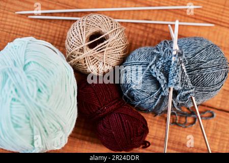 Prepare for winter. Still life shot of multi colored woolen balls and knitting pens on a wooden table. Stockfoto