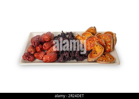 Drei Arten von asiatischen getrockneten Früchten, Bael, Okra und Jujube sind Zutaten für gesunden Kräutertee auf demselben Teller auf weißem Hintergrund. Stockfoto