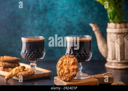 Zwei dampfende Tassen Kaffee und frisch gebackene Plätzchen auf kleinen Holzbrettern Stockfoto