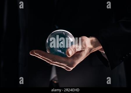 Geschäftsmannshand mit Glaskugel auf schwarzem Hintergrund Stockfoto
