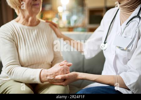 Zugeschnittenes Bild einer Arztin, die ihren älteren Patienten unterstützt und Hoffnung gibt. Eine Frau, die die Seniorin in der Hand hält Stockfoto