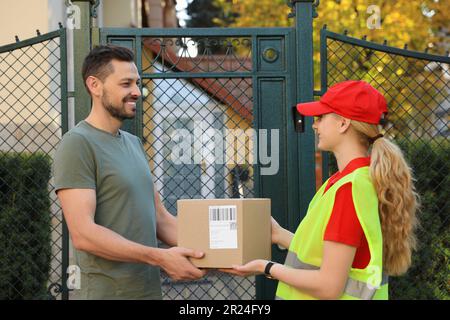 Mann, der ein Paket vom Kurier in Uniform im Freien erhält Stockfoto
