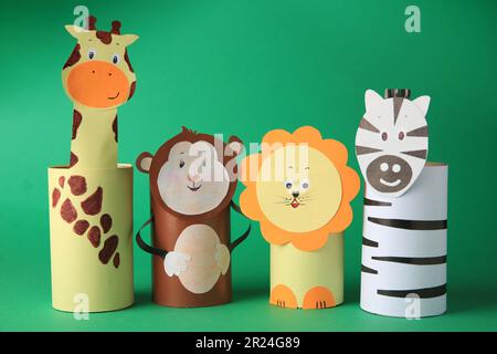 Spielzeugaffe, Giraffe, Löwe und Zebra aus Toilettenpapier auf grünem Hintergrund. Handgemachte Kinderideen Stockfoto