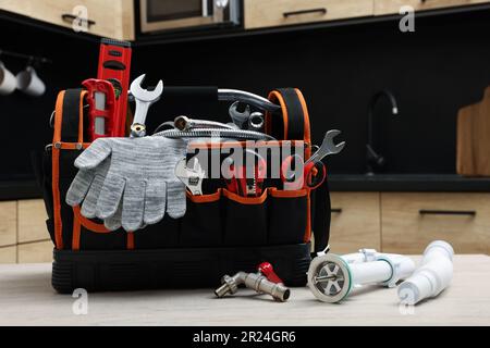 Klempnerhandtasche und Rohre auf Tisch in der Küche Stockfoto