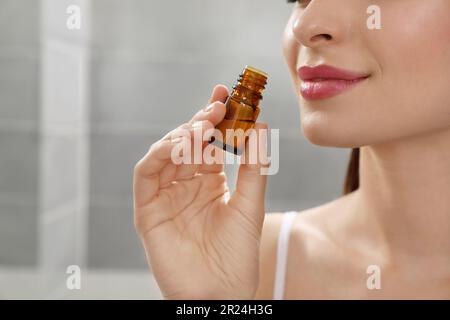 Junge Frau riecht ätherisches Öl drinnen, Nahaufnahme Stockfoto