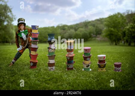 Schöne Frau wie verrückter Hutmacher mit Hüten in der Natur Stockfoto