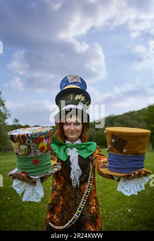 Schöne Frau wie verrückter Hutmacher mit Hüten in der Natur Stockfoto