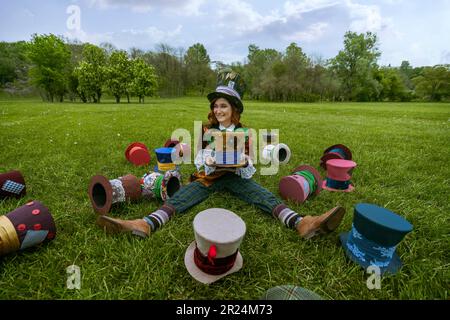 Schöne Frau wie verrückter Hutmacher mit Hüten in der Natur Stockfoto