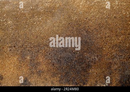Eine Nahaufnahme einer braun-orangefarbenen Betonwand mit rostiger Konsistenz Stockfoto