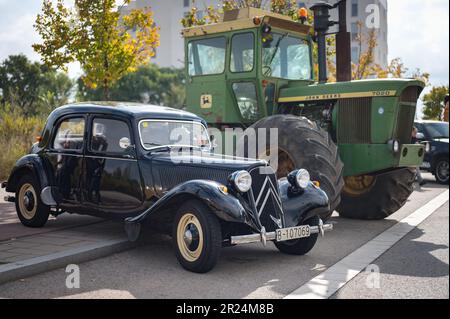 Vorderansicht eines schwarzen französischen historischen Fahrzeugs, das neben einem Traktor geparkt ist, ist es ein Citroen Traction Avant Stockfoto