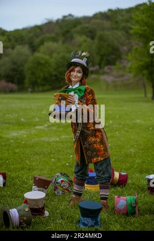 Schöne Frau wie verrückter Hutmacher mit Hüten in der Natur Stockfoto