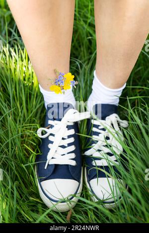 Schöne Freizeitschuhe mit Blumen in Socken. Blumen in blauen Turnschuhen, ein Klassiker. Gehen Sie. Moderne Unisex-Schuhe. Modische, stylische sportliche Freizeitschuhe. Stockfoto