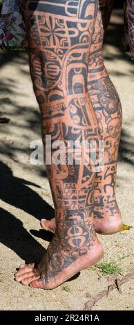 Französisch-Polynesien, Gesellschaftsinseln, Raiatea. Dorfältester mit traditionellen Tattoos bedeckt. Tätowierung am Bein. Stockfoto