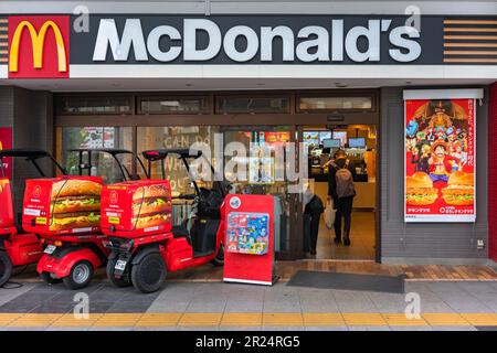 tokio, japan – april 11 2023: Japanische Honda Gyro-Schutzdach-Dreirad-Motorräder für McDelivery, geparkt bei McDonald's mit einem Werbetoster Stockfoto