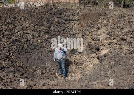 Orichhiv, Ukraine. 16. Mai 2023. Yuri Sukhina, 59, steht in einem Krater, der nach der Explosion der Luftbombe auftauchte, als sein Haus nach dem russischen Bombenangriff in Orichow schwer beschädigt wurde. Nach der aktuellen Situation kontrolliert Russland mehr als 70 % der Oblast Zaporizhia, aber das ehemalige Bezirkszentrum, die Stadt Zaporizhia, steht immer noch unter der Kontrolle der ukrainischen Streitkräfte. Seit März 2023 ist die Stadt Melitopol das Verwaltungszentrum des (von russischen Streitkräften besetzten) Bezirks. (Foto: Andriy Andriyenko/SOPA Images/Sipa USA) Guthaben: SIPA USA/Alamy Live News Stockfoto