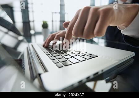 Junger Mann drückt seinen Finger auf den Computer am Tisch im Büro, Nahaufnahme. Stockfoto