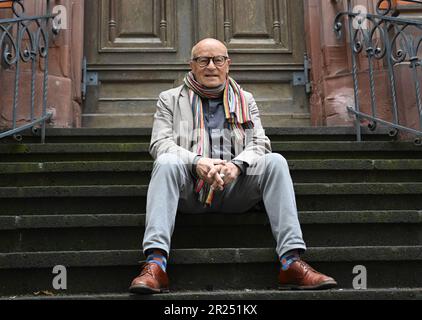 Wiesbaden, Deutschland. 17. Mai 2023. Direktor Volker Schlöndorff sitzt vor Beginn einer Pressekonferenz für die Ausstellung „Volker Schlöndorff. Von Wiesbaden in die Welt' auf einer Treppe der Marktkirche. Die Ausstellung auf der FilmBühne Caligari zeigt Publikationen und Filmserien über das Leben und Werk des preisgekrönten Filmemachers vom 19. Mai bis 18. Juni 2023. Kredit: Arne Dedert/dpa/Alamy Live News Stockfoto