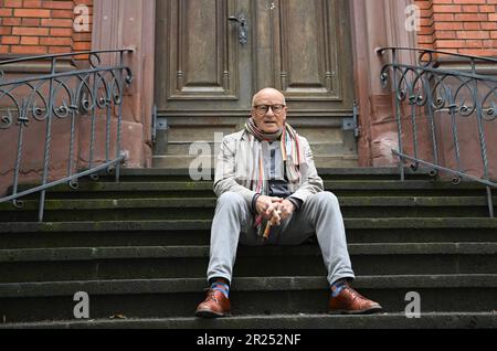 Wiesbaden, Deutschland. 17. Mai 2023. Direktor Volker Schlöndorff sitzt vor Beginn einer Pressekonferenz für die Ausstellung „Volker Schlöndorff. Von Wiesbaden in die Welt' auf einer Treppe der Marktkirche. Die Ausstellung auf der FilmBühne Caligari zeigt Publikationen und Filmserien über das Leben und Werk des preisgekrönten Filmemachers vom 19. Mai bis 18. Juni 2023. Kredit: Arne Dedert/dpa/Alamy Live News Stockfoto