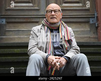 Wiesbaden, Deutschland. 17. Mai 2023. Direktor Volker Schlöndorff sitzt vor Beginn einer Pressekonferenz für die Ausstellung „Volker Schlöndorff. Von Wiesbaden in die Welt' auf einer Treppe der Marktkirche. Die Ausstellung auf der FilmBühne Caligari zeigt Publikationen und Filmserien über das Leben und Werk des preisgekrönten Filmemachers vom 19. Mai bis 18. Juni 2023. Kredit: Arne Dedert/dpa/Alamy Live News Stockfoto