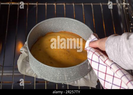 Der Confectioner zieht gebackenen Kuchenteig mit einem Handtuch aus dem Ofen Stockfoto