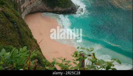 Türkisfarbene Meereswellen Rollen am goldenen Sandstrand von Kelingking bei Sonnenuntergang in Bali Nusa Penida Indonesia. Unberührte tropische Landschaft in Zeitlupe. Stockfoto