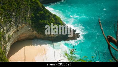 Türkisfarbenes reines Meerwasser am goldenen Sandstrand von Kelingking in Bali Nusa Penida Indonesia. Unberührte tropische Landschaft in Zeitlupe. Stockfoto