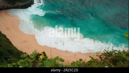 Blaues Ozeanwasser mit riesigen Wellen rollt auf dem goldenen Sandstrand von Kelingking in Bali Nusa Penida Indonesia. Gefährliche Landschaft in Zeitlupe. Stockfoto