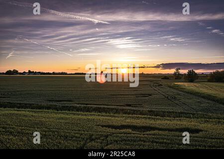 Atemberaubende orangefarbene Sonnenuntergänge über üppigen Feldern im Po-Tal, Norditaliens fruchtbarer Landschaft Stockfoto